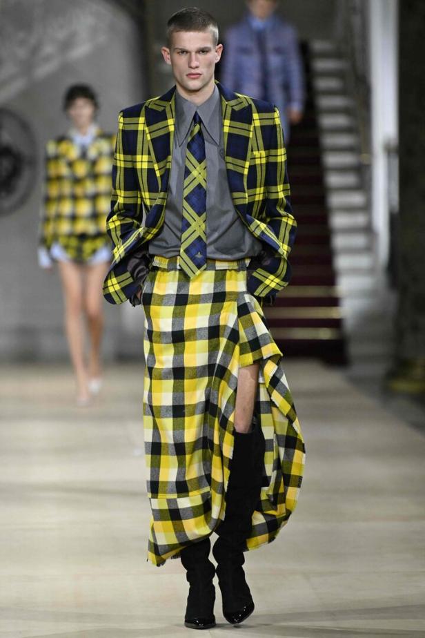 Ein Mann in einem gelb-schwarz karierten Blazer und Rock von Vivienne Westwood auf dem Laufsteg.