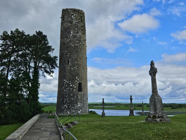 Ein irischer Rundturm und alte Kreuze in Clonmacnoise.