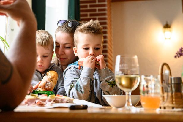 Eine Familie sitzt am Tisch in einem Heurigen und genießt gemeinsam ihre Jause.