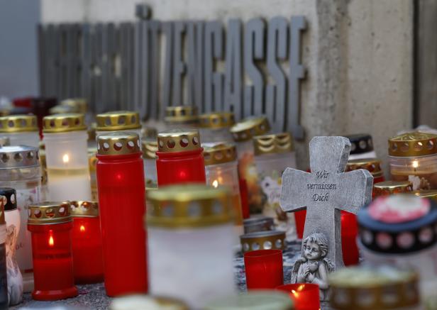 Kerzen und ein Kreuz mit der Aufschrift „Wir vermissen Dich“ vor einem Schulgebäude.