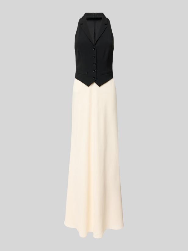 Ein ärmelloses, elfenbeinfarbenes Kleid mit einer schwarzen Weste darüber.