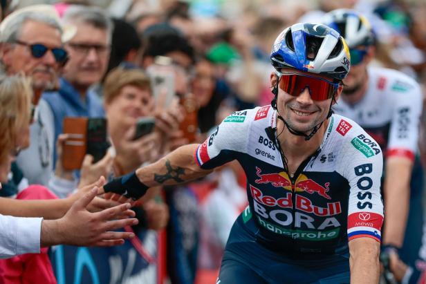 Ein Radfahrer von Red Bull Bora gibt Fans die Hand.