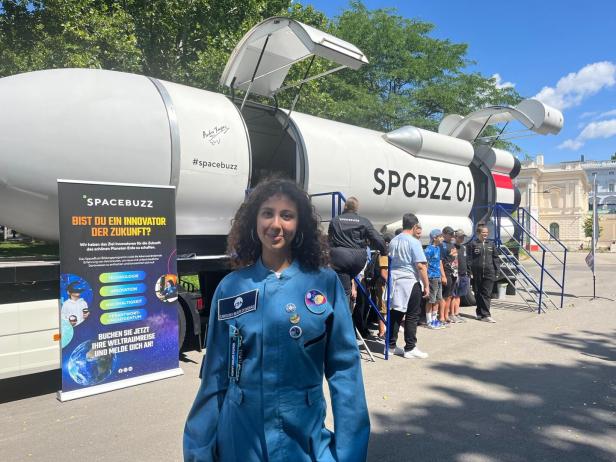 Eine Frau vor einer Spacebuzz-Rakete mit Kindern und einem Werbebanner.