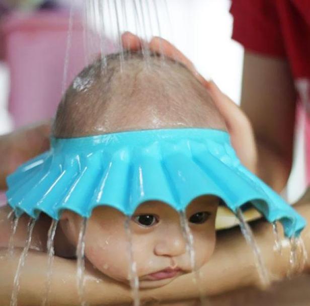 Ein Baby mit einer blauen Duschhaube wird gebadet.