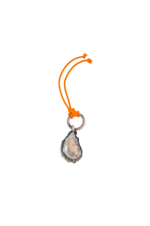 Ein Anhänger in Form einer Auster mit einer kleinen Perle, an einer orangefarbenen Schnur.