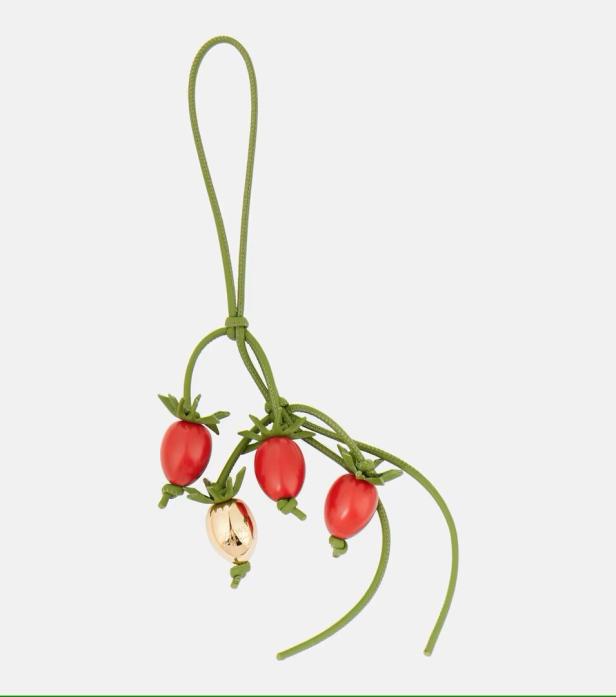 Ein Loewe-Anhänger mit roten und goldfarbenen Erdbeeren an einem grünen Band.