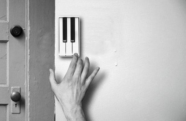 Eine Hand berührt einen Lichtschalter in Form einer Klaviertastatur neben einer Tür.