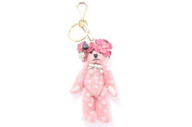 Ein rosa Prada-Bär-Taschenanhänger mit Blumenkopfschmuck.