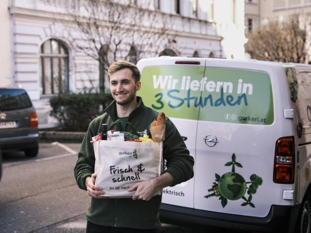 Ein Lieferant von gurkerl liefert eine Einkaufstasche mit Essen. 