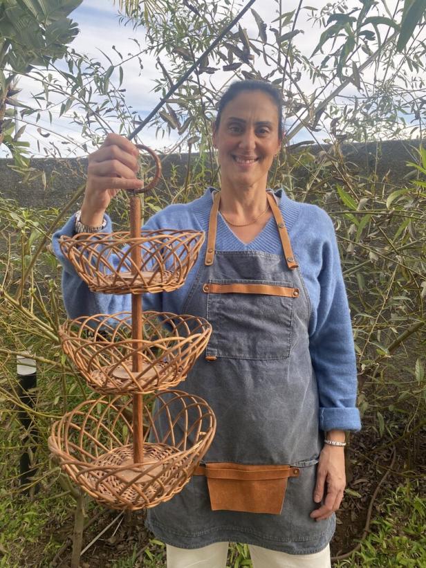Eine Frau hält eine dreistöckige Etagere aus Weide in die Höhe.