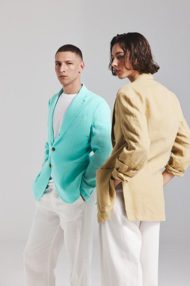 Zwei Models präsentieren Sommerblazer in Türkis und Beige mit weißen Hosen.