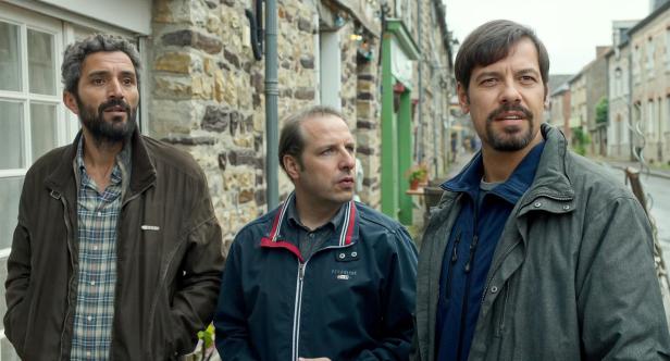 Drei Männer stehen vor einem Gebäude in einer Stadt.