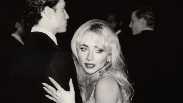 Eine Frau mit blonden Haaren und ein Mann im Anzug auf einer Veranstaltung.