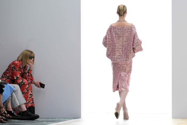 Anna Wintour bei einer Fendi Modenschau; ein Model präsentiert ein rosafarbenes Paillettenensemble.