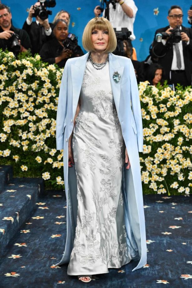 Anna Wintour auf dem roten Teppich der Met Gala in einem silbernen Kleid und hellblauen Mantel.