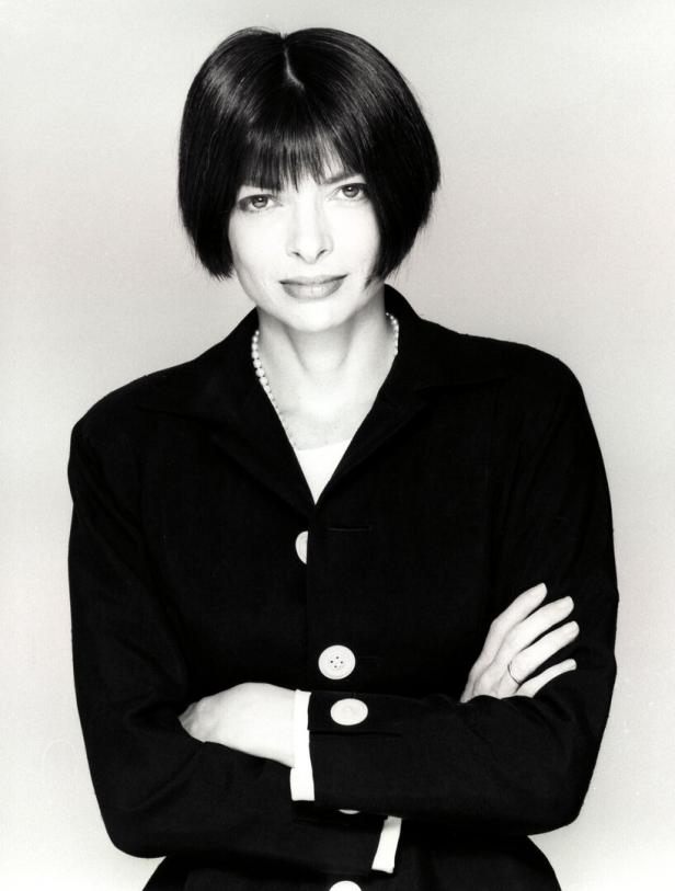Anna Wintour mit verschränkten Armen in einem schwarzen Blazer.