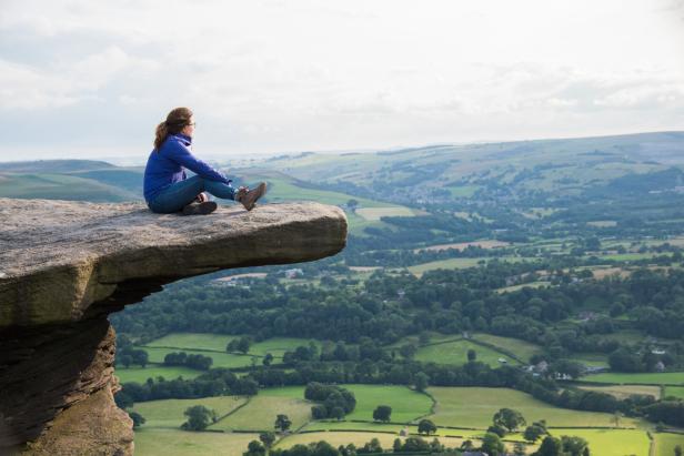 Eine Frau sitzt auf einem Felsen im Hope Valley im Peak District.