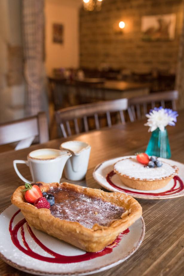 Zwei Törtchen mit Puderzucker und Beeren auf Tellern in einem Café.
