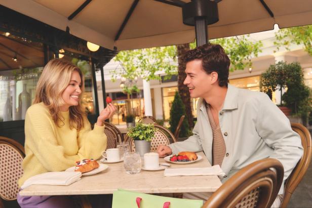 Eine Frau und ein Mann sitzen an einem Tisch in einem Restaurant und genießen ihr Essen und lachen dabei.