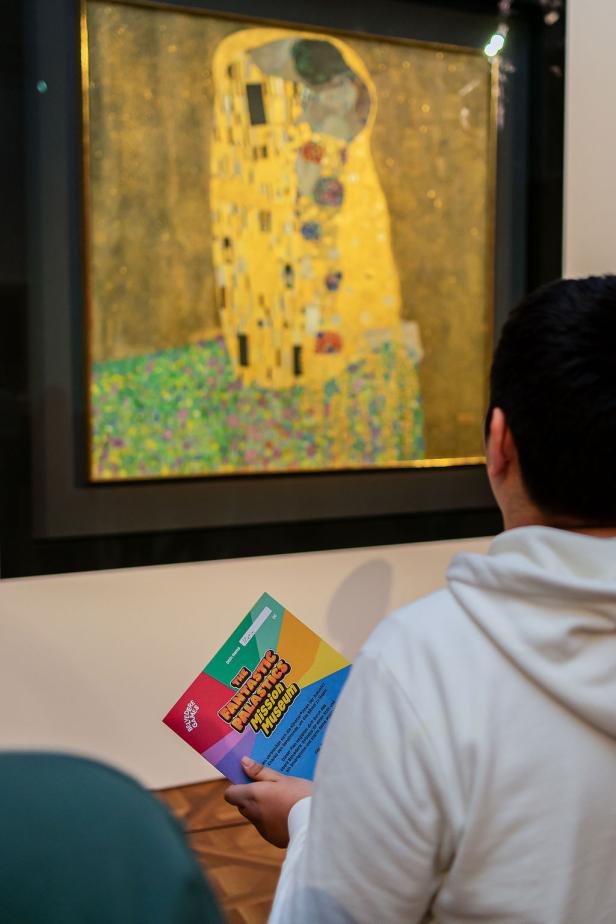 Ein junger Mann mit der Game Map vor Klimts "Der Kuss" im Museum Belvedere.