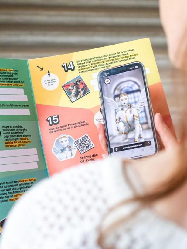 Eine junge Besucherin scannt mit ihrem Smartphone den QR Code der Spielanleitung