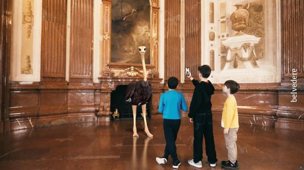 Im Museum schauen drei Kinder fasziniert auf einen Vogel Strauß.