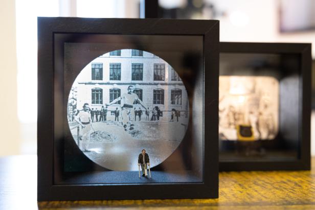 Ein Diorama zeigt einen Mann mit Krücken vor einem historischen Foto einer Seiltänzer-Aufführung.