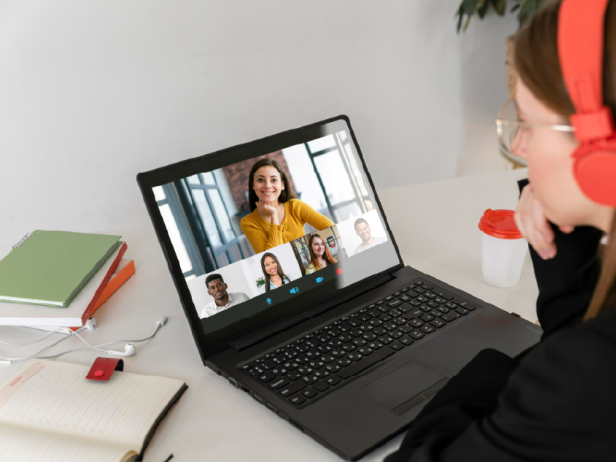 Frau mit Brille und roten Kopfhörern sitzt vor einem Laptop in einem Videocall