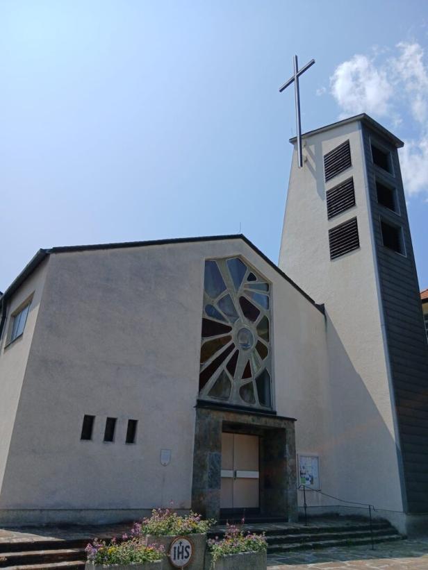 Eine moderne Kirche mit einem Turm und einem Kreuz unter blauem Himmel.