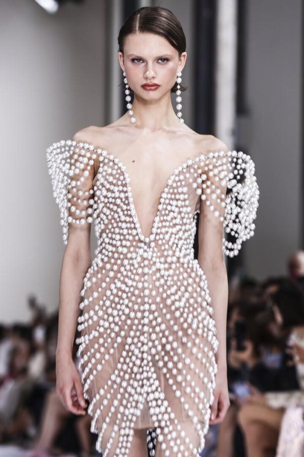 Ein Model präsentiert ein Kleid mit Perlenbesatz auf dem Laufsteg der Paris Fashion Week.
