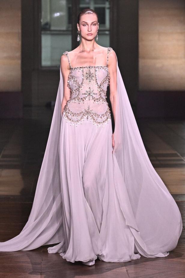 Ein Model präsentiert ein langes, helles Kleid von Georges Hobeika auf einer Modenschau in Frankreich.