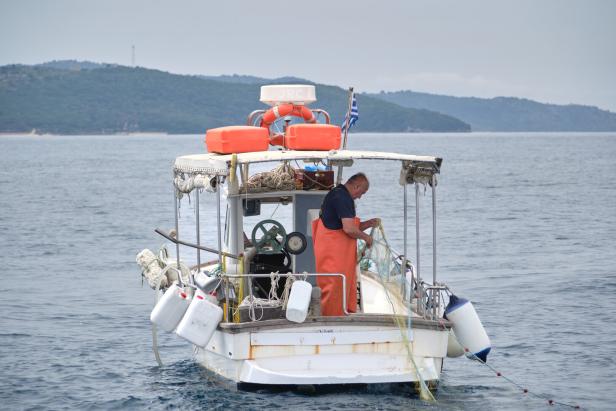 Ein Fischer auf einem Boot auf dem Meer, möglicherweise in der Nähe von Korfu.