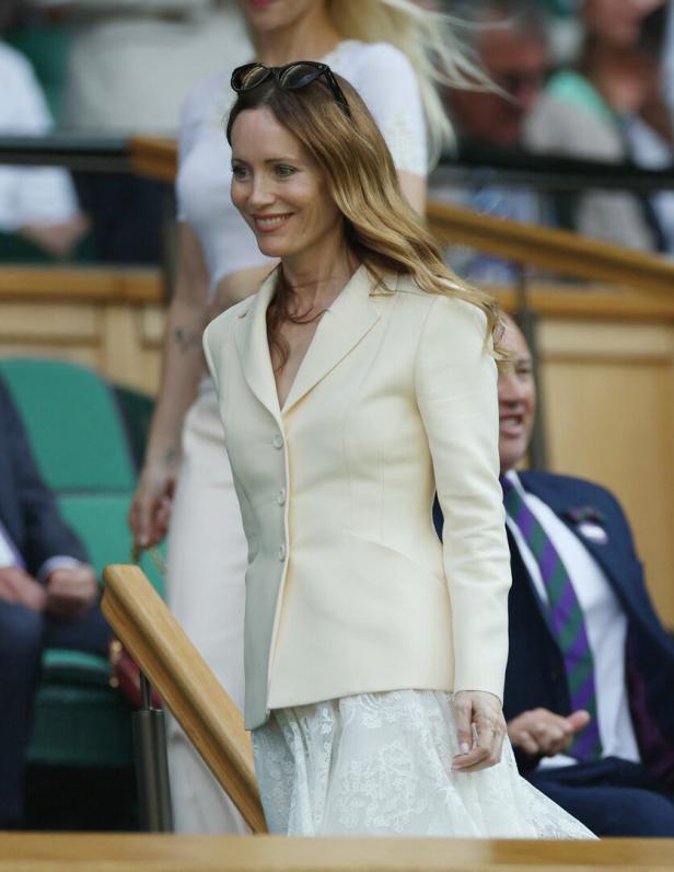 Eine Frau in einem hellen Blazer und Rock bei einem Wimbledon-Tennismatch.