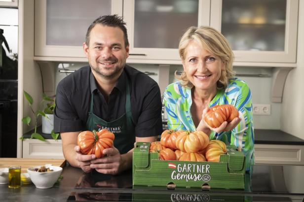 Ein Mann und eine Frau halten eine Kiste mit frischen Tomaten in den Händen.