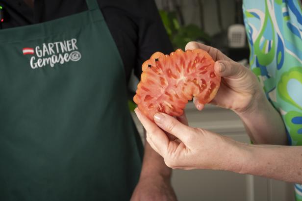 Eine Frau zeigt eine Tomate.