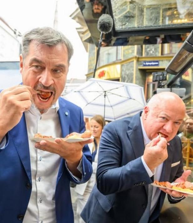 Markus Söder mit Wurst. Im Hintergrund Christian Stocker mit Wurst.