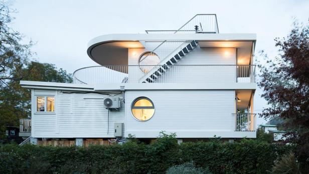 Ein modernes, weißes Haus mit runden Fenstern und Außentreppe.