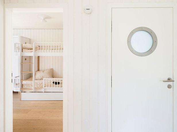 Blick durch eine Tür auf ein weißes Kinderzimmer mit einem Etagenbett.