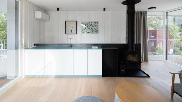 Ein modernes Wohnzimmer mit einem Kaminofen und weißen Einbauschränken.