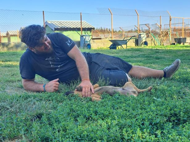 Stephan Scheidl kuschelt mit einem Hund im Gras.