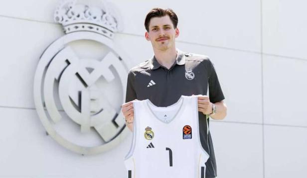Ein Mann hält ein Basketballtrikot von Real Madrid mit der Nummer 1 in der Hand.