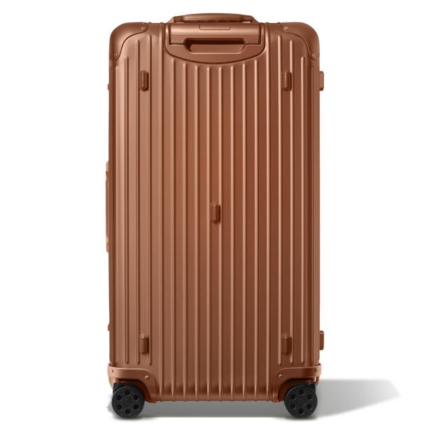Ein bronzefarbener Rimowa-Koffer steht aufrecht.