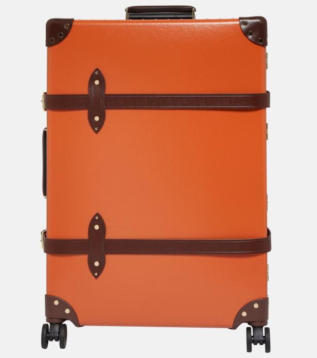 Ein orangefarbener Koffer mit braunen Lederriemen und Eckverstärkungen.