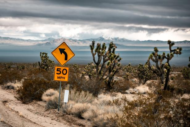 Ein gelbes Verkehrsschild mit der Aufschrift „50 MPH“ in einer Wüstenlandschaft.