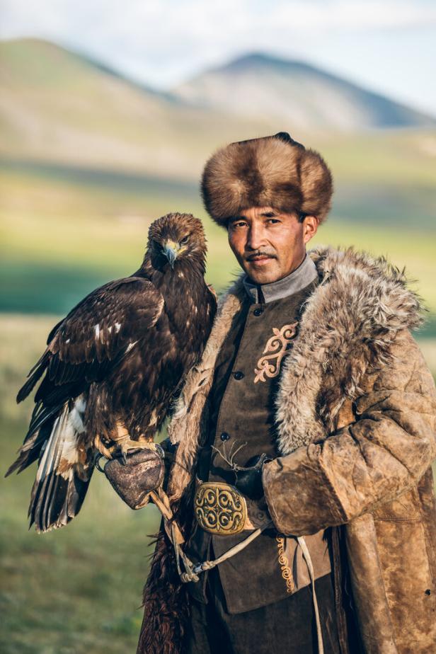 Ein kasachischer Adlerjäger mit seinem Steinadler in der mongolischen Steppe.