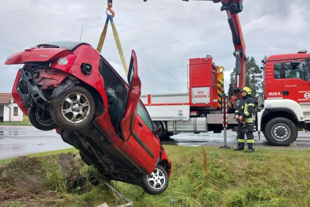 Ein rotes Auto wird von einem Feuerwehrkran angehoben.