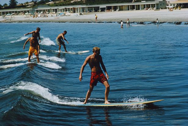 Mehrere Surfer auf einer kleinen Welle.