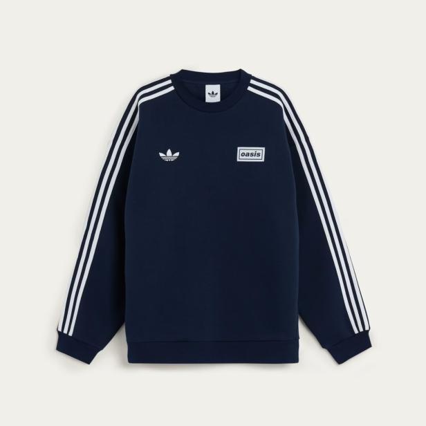 Ein marineblauer Adidas-Pullover mit weißen Streifen und dem „Oasis“-Logo.
