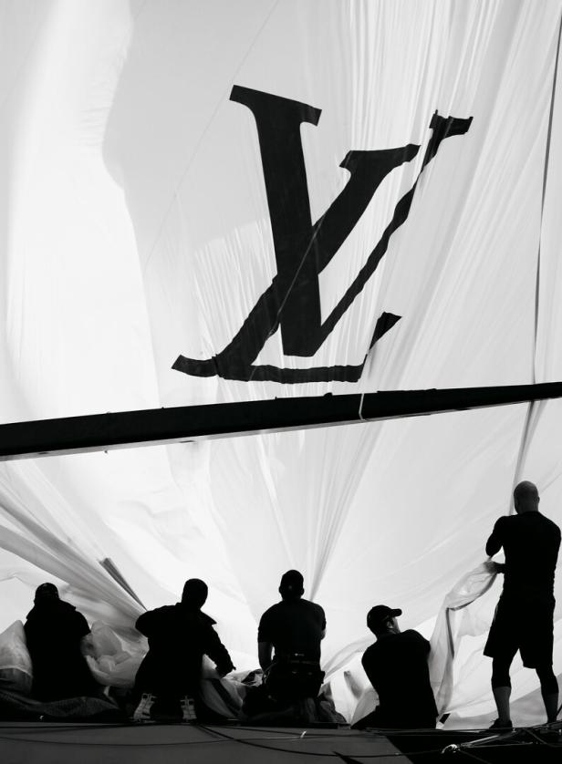 Arbeiter hantieren mit einem großen Segel mit dem Louis Vuitton-Logo.