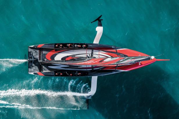 Ein rot-schwarz-weißes America's-Cup-Boot rast auf dem Wasser.
